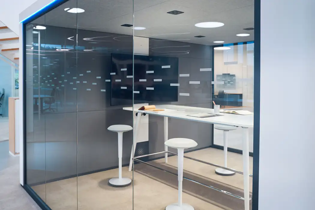 Presentation setup with tv and high desk within a glass office pod